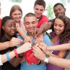 large-group-of-young-people-holding-a-piggy-bank-putting-in-coins-and-smiling